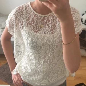 Vit blommig spetsblus - Säljer en superfin vit blus i spets med blommigt mönster. Blusen är ärmlös med lös passform och rund halsringning. Det är ett linne inuti spetsen. Osäker på storlek men tror att det är en stor barnstorlek som xs 💗💗