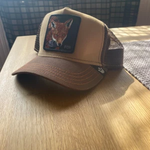  Brun och beige truckerkeps  - Snygg truckerkeps som är brun och beige med en clean räv på som matchar bra med dom andra färgerna. Bara att höra av sig vid minsta lilla fråga!