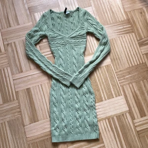Grön stickad kortklänning H&M Divided - Supersnygg ljusgrön stickad klänning från H&M Divided i storlek XXS. Modellen är figurnära med lång ärm och v-ringad hals. Klänningen har ett grovt kabelstickat mönster och ribbade kanter som ger en cool och trendig look. Perfekt för dig som gillar comfy men ändå stylish vibes.