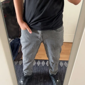 Grå jeansbyxor i rak modell - Säljer ett par grå jeansbyxor med klassisk femficksdesign och rak passform. Byxorna har normal midja och är tillverkade i mjukt jeanstyg. Perfekta för dig som gillar en enkel och stilren look.