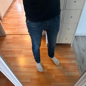 Replay Anbass Jeans - Säljer ett par blå Replay Anbass jeans med slim passform. Jeansen har klassisk femficksdesign, snygga slitningar och detaljerade bakfickor. De är tillverkade i stretchig denim för en bekväm och tight look. Perfekta för dig som gillar en modern och smal siluett. Model är 185 70kg