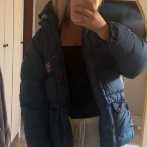Mörkblå dunjacka från Fjällräven - Säljer en mörkblå dunjacka från Fjällräven. Riktigt skön jacka som man aldrig fryser i på vintern, använd fåtal gånger därav priset. Bara att höra av er om ni har frågor💗