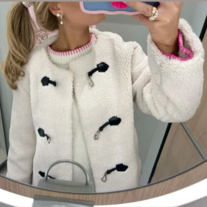 Vit teddyjacka från Gina Tricot - Supermysig vit teddyjacka från Gina Tricot med svarta detaljer och coola spännen framtill. Jackan har rund halsringning, lång ärm och är fodrad på insidan. Helt slutsåld och väldigt populär! Använd endast en gång.