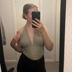Halterneck glitter top  - Otroligt fin topp som har ett glittrande tyg och knytdetalj där bak med en öppen rygg. Knappt använd, så mycket bra skick!  Normal i storleken.