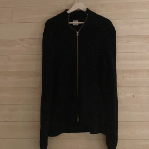 Svart stickad kofta med dragkedja från Zara - Säljer en svart stickad kofta från Zara i storlek M. Koftan har en hel dragkedja framtill och är långärmad med en klassisk, enkel design. Perfekt för lager-på-lager och passar till många olika stilar. Riktigt nice full zip!