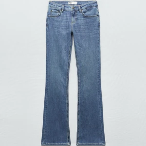 Blå bootcut jeans låg midja Zara - Snygga blå bootcut jeans från Zara med låg midja. Klassisk femficksmodell i mjukt denimtyg som sitter skönt och har en lätt utsvängd passform nertill. Perfekta för dig som gillar en retroinspirerad look.