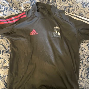 Fotbollströja - Grå fotbollströja med Real Madrids logga från Adidas. Knappt använd. Min pojkväns gamla men funkar absolut för en tjej oxå! Storlek XS men passar S. Tvättar allt innan, skriv för mer bilder eller om du har några frågor.💞