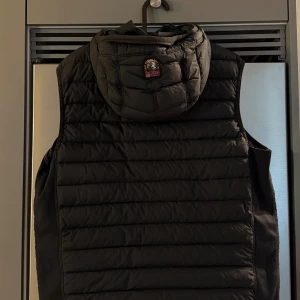 Svart dunväst från Parajumpers - Säljer en svart dunväst från Parajumpers med huva och klassisk logga på ryggen. Västen är sparsamt använd ser ny ut! 