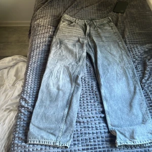 Grå loose fit jeans 152 - Säljer ett par grå loose fit jeans i storlek 152 med justerbar midja. Jeansen har klassisk femficksdesign och raka ben. Perfekta för dig som gillar en avslappnad och trendig look.