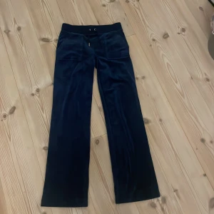 Mörkblå Juicy Couture - Mörkblå byxor från Juicy Couture med bred resår i midjan och snörning framtill. Tappat en av de silvriga grejen på snöret 