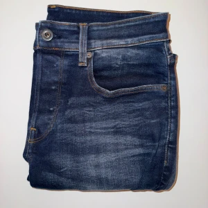 G-Star RAW Mörkblå Jeans - G-Star RAW Mörklblå Jeans, Slim fit med kontrastsömmar. Jeansen har inga spår av större användning och har inga skador