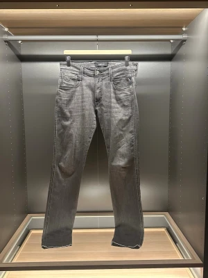 Replay Anbass - Snygga Replay Anbass jeans i en tvättad grå färg med klassisk femficksdesign och med en slim fit passform. Hör av er vid frågor eller funderingar
