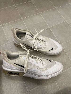 Nike Air Max vita sneakers strl 43 - Nike Air Max sneakers i vitt med svarta detaljer och synlig Air Max-dämpning i sulan. Ovandelen är i mesh och syntet med snörning och rund tå. Snygg och sportig design med AIRMAX-logga på sidan av sulan. Perfekt för dig som gillar streetwear och sportig stil.