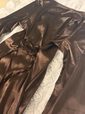 Brun silkesklänning - Brun silkesklänning med breda ärmar och brytning i bak.