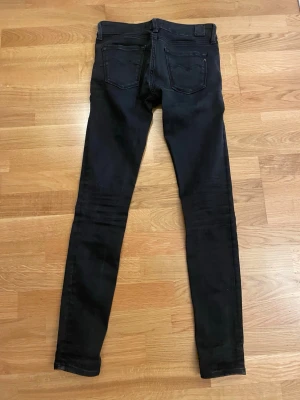 Replay svarta skinny jeans - Svarta jeans från Replay med skinny passform och klassisk femficksdesign. Byxorna har låg midja och är gjorda i stretchigt jeansmaterial för en tajt och bekväm känsla. Snygga detaljer med Replay-logga på fickan och bak vid linningen.