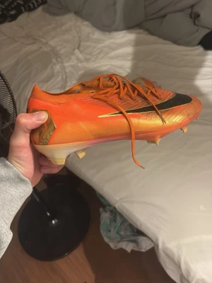 Nike Air Zoom orange fotbollsskor - Säljer ett par Nike Air Zoom fotbollsskor i en riktigt fet orange färg med svarta och guldiga detaljer.  Skorna är limited edition o finns inte att köpa längre, säljer dem pga att de inte passar, andvända i 2 träningar , storlek 45 , pris kan diskuteras 