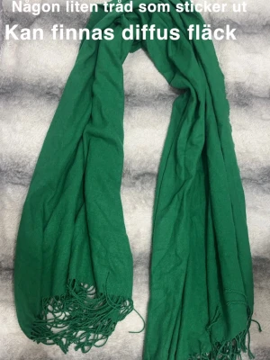 Grön sjal med fransar - Snygg grön sjal med långa fransar i ändarna. Perfekt att slänga över axlarna för en cool och avslappnad look. Färgen är riktigt poppande. Passar till både jacka och tröja för att ge outfiten lite extra färg.🌸 Lapp borta. Finns någon liten tråd som sticker ut ( ej hål). Kan finnas någon diffus fläck. 