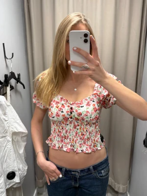 Blommig croppad blus med puffärm - Så  söt blommig blus med puffiga korta ärmar och croppad passform. Smockad midja och volangkant nedtill💘💘 jag har vanligtvis S/M💗
