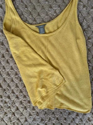 Gul linnetopp från Lindex XS - Säljer en gul linnetopp från Lindex i storlek XS. Toppen har en enkel och stilren design med rundad halsringning och ärmlös modell. Materialet är mjukt och bekvämt, perfekt för varma dagar. Passar dig som gillar minimalistisk stil och vill ha en färgklick i garderoben.