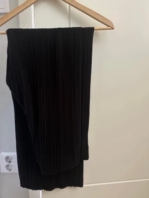 Svarta plisserade byxor Gina Tricot M - Ett par svarta plisserade byxor. Byxorna har en resår i midjan. Har 4 små hål på baksidan som bör kunna sys av den händige. I övrigt inget att anmärka på :)