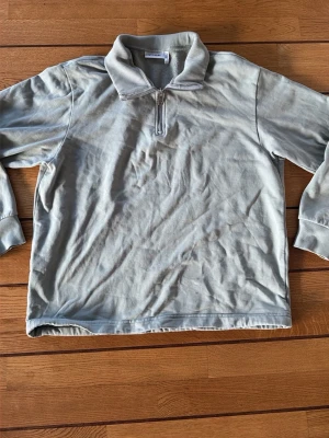 Grå half zip tröja från Weekday - Säljer en grå långärmad tröja från Weekday i storlek M. Tröjan har en bred krage och en snygg half zip-dragkedja framtill. Materialet är mjukt och känns som bomull, perfekt för chill dagar. Passformen är normal och färgen är ljusgrå.