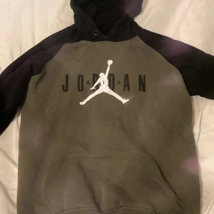 Jordan hoodie XXL i svart och olivgrön - Säljer en fett snygg Jordan hoodie i storlek XXL. Tröjan har svart huva och ärmar, med olivgrön kropp och stor vit Jumpman-logga på bröstet. Klassisk känguruficka framtill och mjukt material som är perfekt för chill eller streetwear. Hoodien har en loose passform.