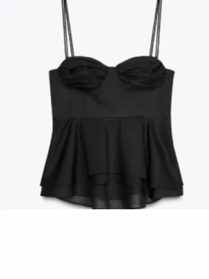 Svart topp - Säljer en svart korsett-topp med tunna axelband och snygg volang nedtill. Populär topp från Zara, endast använd en gång. 