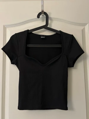 Svart ribbad topp  Gina Tricot - Kortare modell med stretch. Använd 1 gång. Storlek S
