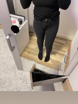 Svarta skinny jeans - Säljer ett par svarta skinny jeans med klassisk femficksdesign och knappgylf. Jeansen har en tight passform och är tillverkade i stretchigt denimtyg som sitter snyggt och bekvämt. Perfekta för dig som gillar en stilren och enkel look.