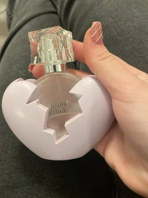 Ariana Grande parfym  - Snygg parfym från Ariana Grande med ett unikt hjärtformat fodral. Perfekt för dig som vill ha en trendig och personlig accessoar på sminkbordet. Halvfull
