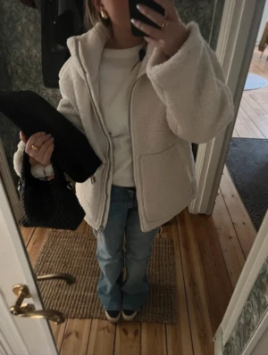 Beige teddyjacka med dragkedja - Säljer denna populära teddyjacka med hög krage och dragkedja framtill. Jackan har en loose passform och stora fickor på sidorna. Perfekt för dig som gillar mysiga och trendiga plagg med fluffig känsla. Den har lite smink fläckar som säkert går bort i tvätten (kan skicka bild)