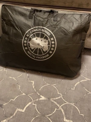 Svart Canada Goose parkajacka med päls - Svart parkajacka från Canada Goose med äkta päls på huvan och tydlig logga på ärmen. Jackan har dragkedja med logotyp, tryckknappar och är fodrad med dun och fjädrar. Perfekt för kalla vinterdagar och har en klassisk, stilren look.
