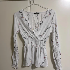 Blommig blus  - Jag säljer en blommig blus som är perfekt till sommaren där den är tunn i materialet. Den markerar midjan på mitten och är väldigt fin på!