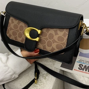 Svart axelväska från Coach - Snygg svart axelväska från Coach med klassisk C-logga i guld framtill. Väskan har en rektangulär form, justerbar axelrem och detaljer i svart skinn. Framsidan har Coachs signaturmönster i beige och brunt. Perfekt för dig som gillar stilrena accessoarer med lyxig känsla.