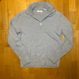  ribbad half zip tröja Jack & Jones - Säljer en stilren grå ribbad tröja från Jack & Jones med half zip och hög krage. Tröjan är långärmad och har en clean look som funkar till många olika outfits. Materialet är mjukt och stickat, perfekt för kyliga dagar.