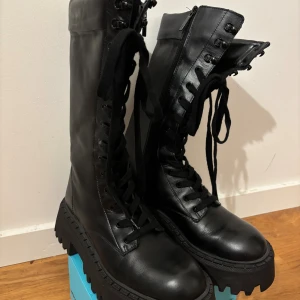 Zara boots - Säljer ett par svarta höga boots från Zara med grov plattformssula och snörning hela vägen upp. Skorna har dragkedja på sidan för enkel påtagning. 