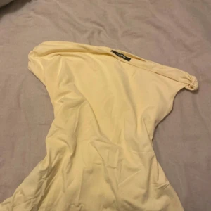 Ljusgul oneshoulder topp Gina Tricot - Supersnygg ljusgul topp från Gina Tricot i mjukt bomullsmaterial. Toppen har oneshoulder-design med en cool knutdetalj på axeln och en elastisk kant för extra komfort. Perfekt för dig som vill sticka ut med en enkel men trendig look.