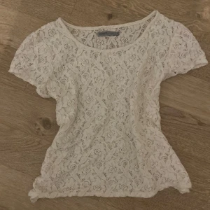 Vit spetsblus från Soaked in Luxury - Supersöt vit blus i spets från Soaked in Luxury, storlek M men passar som S. Blusen har korta ärmar och ett blommigt spetsmönster. Rund halsringning och mjukt material. Perfekt för dig som gillar Stockholmsstil.