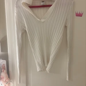 Vit ribbad tröja från Visual Clothing Project - Säljer en vit långärmad tröja från Visual Clothing Project i storlek S. Tröjan är ribbad med v-ringning och har en mjuk, stretchig känsla. Perfekt att styla med jeans eller kjol för en clean look. OBS! Den är inte så tight nedertill😭