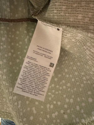 Ljusgrön långärmad topp - Söt ljusgrön blommig blus topp mönstrad / prickig, vita prickar, v-ringad omlott urringning, resor i midjan / peplum topp, liten puffärm, volang vid armslut. Storlek XS-S. 