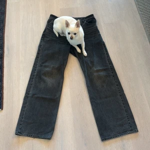 Svarta vida jeans från Monki, stl 32 - Säljer ett par svarta jeans från Monki i storlek 32. Jeansen har en rak och vid passform med fem fickor och knappgylf. Tillverkade i 100% bomull för en skön och stadig känsla. Perfekta för dig som gillar en avslappnad och trendig look.