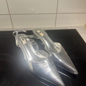 Silvriga pumps med spetsig tå - Säljer ett par glansiga silvriga pumps med spetsig tå och smal klack.