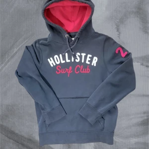 Mörkblå hoodie Hollister Surf Club - Asfet hoodie from hollister i stl M men passar S. Är 188 och är hyfsat kort på mig, den skulle passa dig mellan 174-184. Priset är diskuterat så hör gärna av dig vid frågor :)