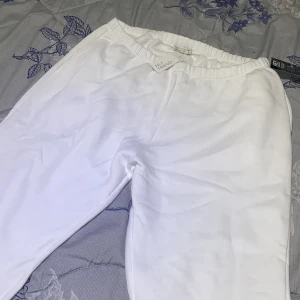 Vita mjukisbyxor från NLY Trend - Säljer ett par fräscha vita mjukisbyxor från NLY Trend. De har en elastisk midja och är tillverkade i mjukt bomullsmaterial. Perfekt för chill dagar eller när du vill ha det extra bekvämt. Snygg och enkel design utan synliga detaljer.