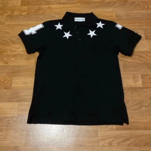 Svart pikétröja med vita stjärnor - Oanvänd polo i bra skick. Givenchy-inspirerad design. Säljer då den inte passar längre.
