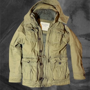 Grön parkajacka Abercrombie & Fitch - Extremt varm och eftertraktad vinterjacka från Abercrombie. Med dubbla lager och dun mot kroppen blir den värmande och bekväm. Inga skavanker. Jackan är en perfekt present till jul eller liknande. Tveka inte att höra av dig om frågor.