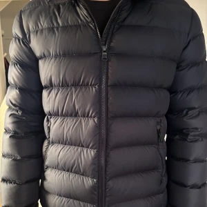 Marinblå Colmar pufferjacka herr - Säljer en marinblå pufferjacka från Colmar Originals med diskret logga på ärmen och insidan. Jackan har quiltad design, dragkedja framtill och sidofickor med zip. Perfekt för kalla dagar.