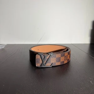 Bälte  - Helt nytt brun rutigt bälte med svart logga 