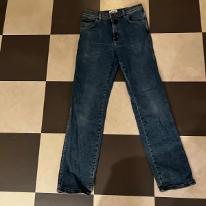 Wrangler Texas jeans blå W30 L32 - Säljer ett par klassiska Wrangler Texas jeans i mörkblå tvätt med raka ben och normal passform. Jeansen har fem fickor, snygga kontrastsömmar och Wrangler-logga på bakfickan. Materialet är slitstarkt denim i bomull. En defekt som visas på tredje bilden