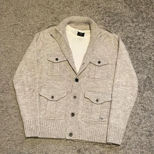 Vit Cardigan - Tjena! Säljer en trendig stilren Vit/ Beige cardigan! 🙌🏻Perfekt för kalla dagar! ❄️Tröjan är i nyskick 9,5/10. Tröjan har klassiska fickor och knappar upp till med en stil som siktar på ”oldmoney”, men funkar till nästan vilken stil som helst!💡Tveka inte på att höra av er!💪🏼